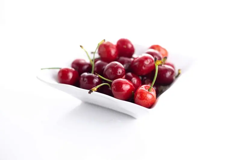 Cerises dans un bol blanc sur fond blanc