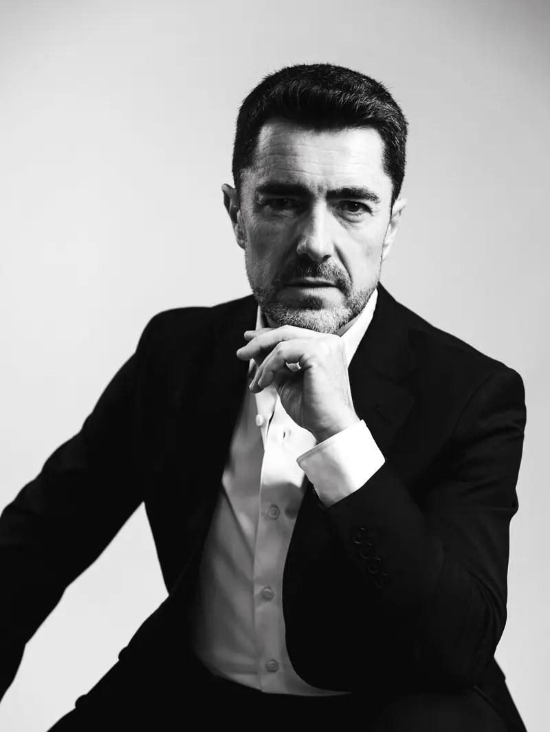 Portrait en noir et blanc du chef de chœur Esteban Urzelai, assis, la main sur le menton
