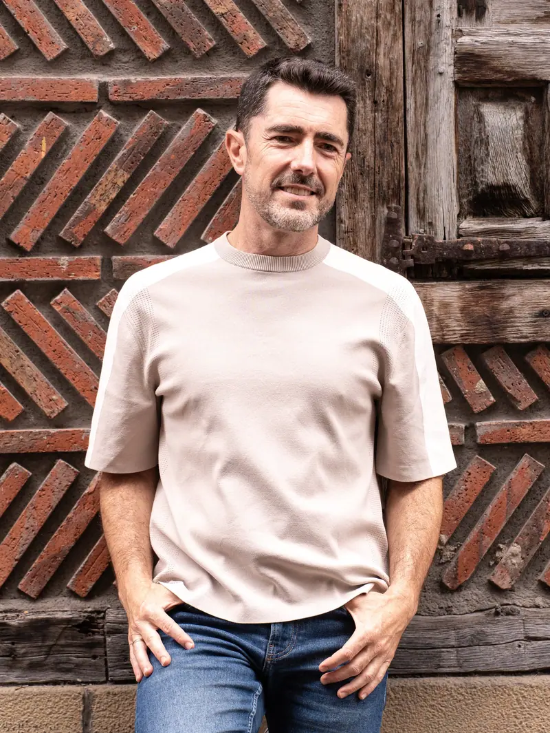 Esteban Urzelai sonriendo junto a una puerta de madera