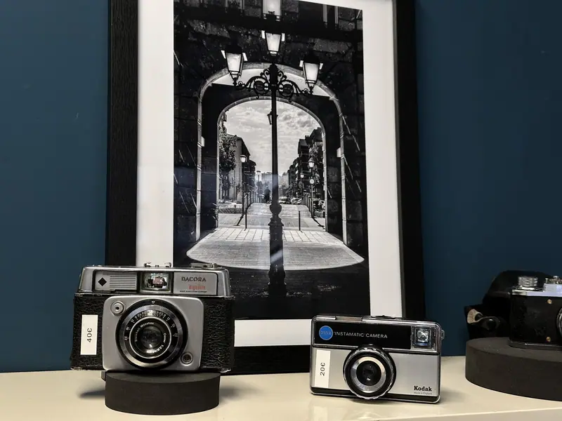 Photo noir et blanc encadrée à côté de deux appareils argentiques à vendre